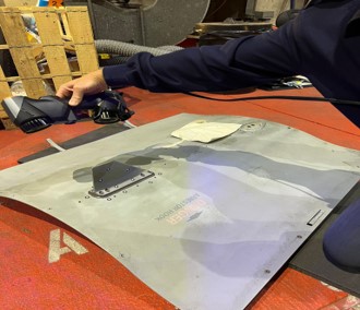 a 3D scanner is used to scan a large piece of metal lying on a hangar table